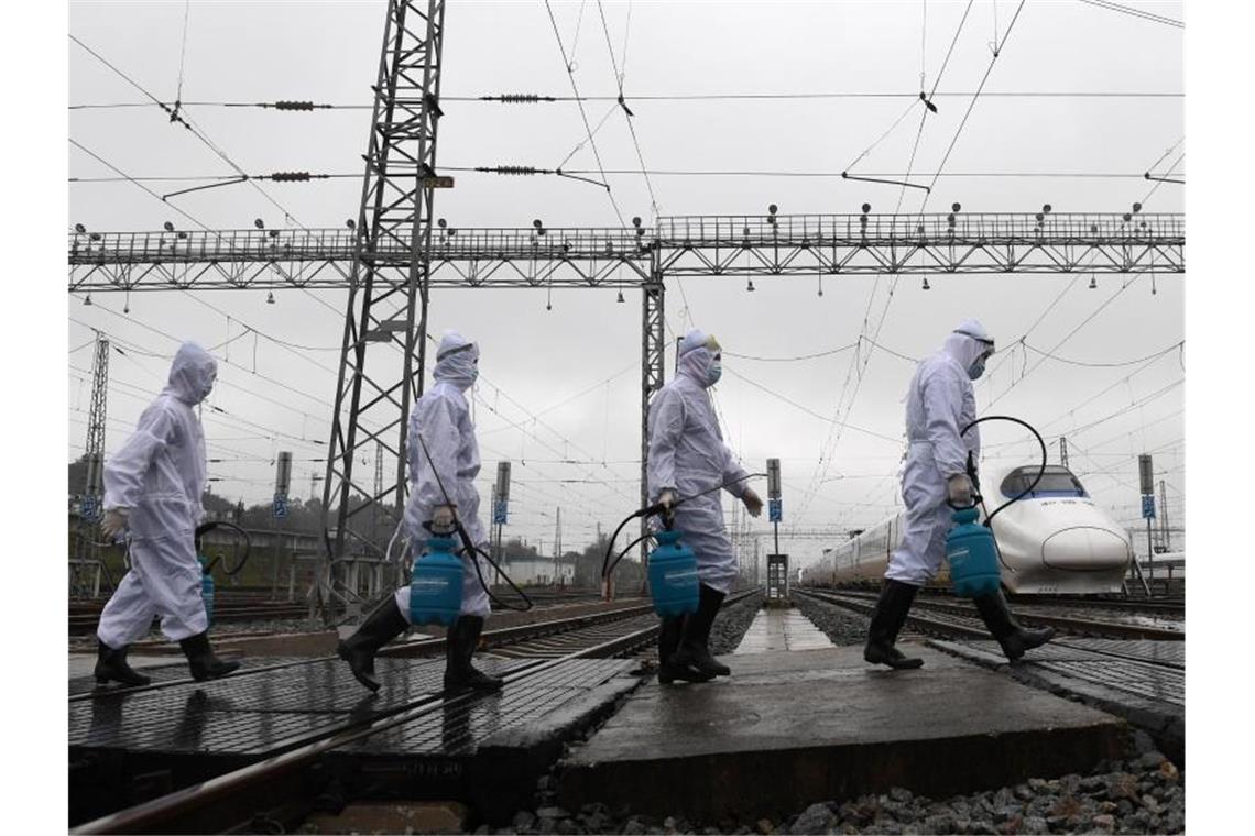 Mitarbeiter der Bahn sind in der chinesischen Stadt Guangxi auf dem Weg zu Zügen, um diese zu desinfizieren. Foto: Lu Boan/XinHua/dpa