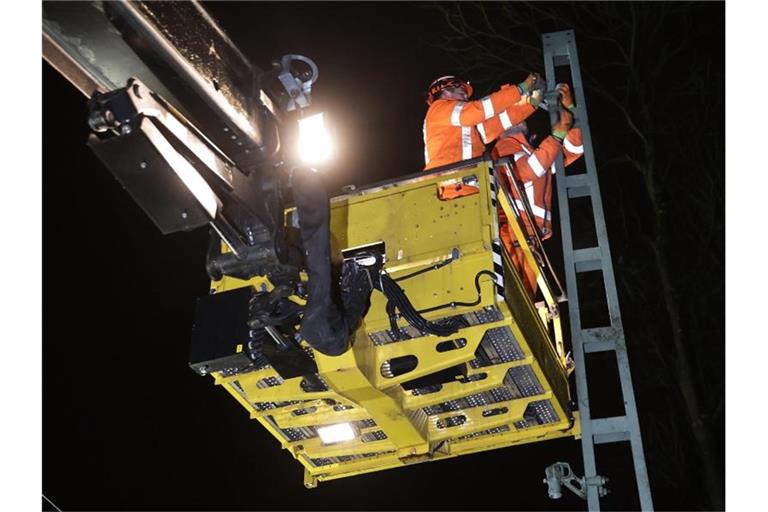 Mitarbeiter der Deutschen Bahn reparieren die Aufhängung des stromführenden Strangs einer Oberleitung nach dem Sturm. Foto: David Young/dpa