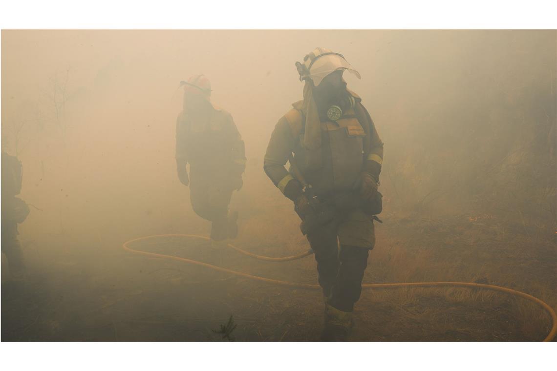 Wo es aktuell in Europa brennt Mitarbeiter der Feuerwehr stehen im Rauch während eines Einsatzes zur Bekämpfung eines Waldbrandes beim spanischen Crecente.