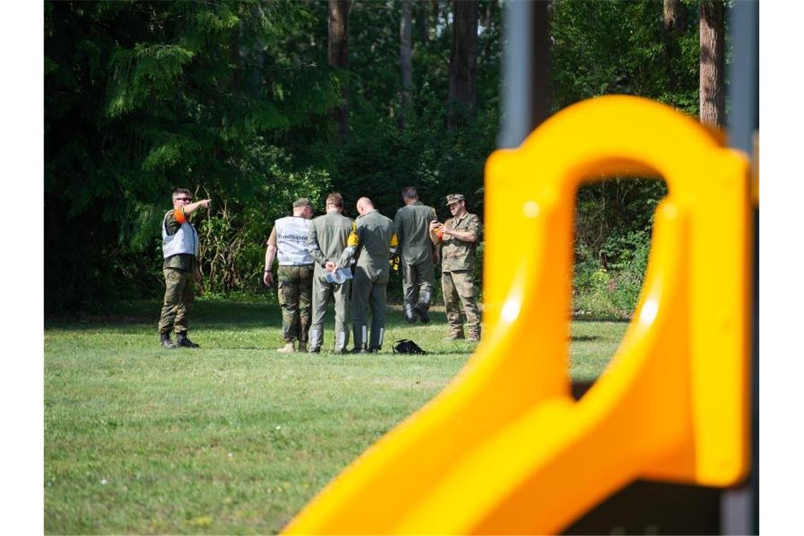 Mitarbeiter der Flugsicherheit der Bundeswehr untersuchen ein Wrackteil auf der Spielwiese eines Kindergartens. Foto: Christophe Gateau