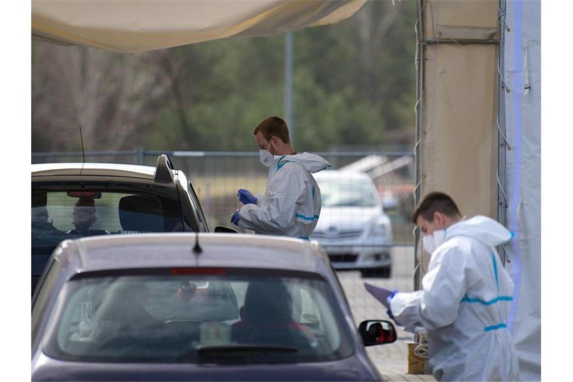 Mitarbeiter der Johanniter-Unfall-Hilfe e.V. testen in einem Zelt des „Drive in“-Corona-Test in Oranienburg die Insassen zweier Autos auf Corona. Foto: Soeren Stache/dpa