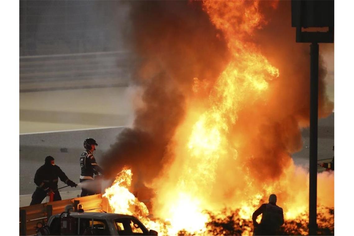 Mitarbeiter der Rennstrecke löschen das brennende Auto von Romain Grosjean. Foto: Brynn Lennon/Pool Getty/dpa