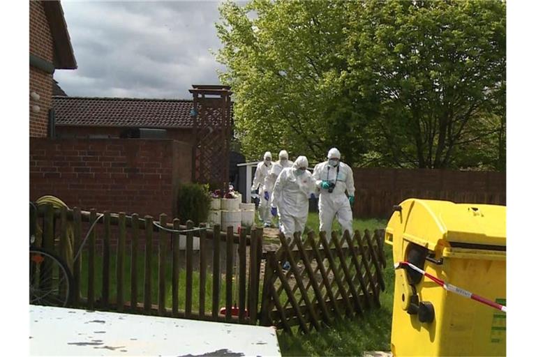 Mitarbeiter der Spurensicherung gehen durch den Garten bei einem Wohnhaus. Foto: -/TNN/dpa