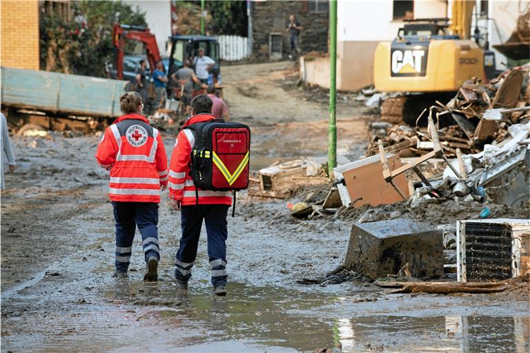Mitarbeiter des DRK gehen im Juli durch eine verschlammte Straße in Ahrweiler. Foto: P. Köhler