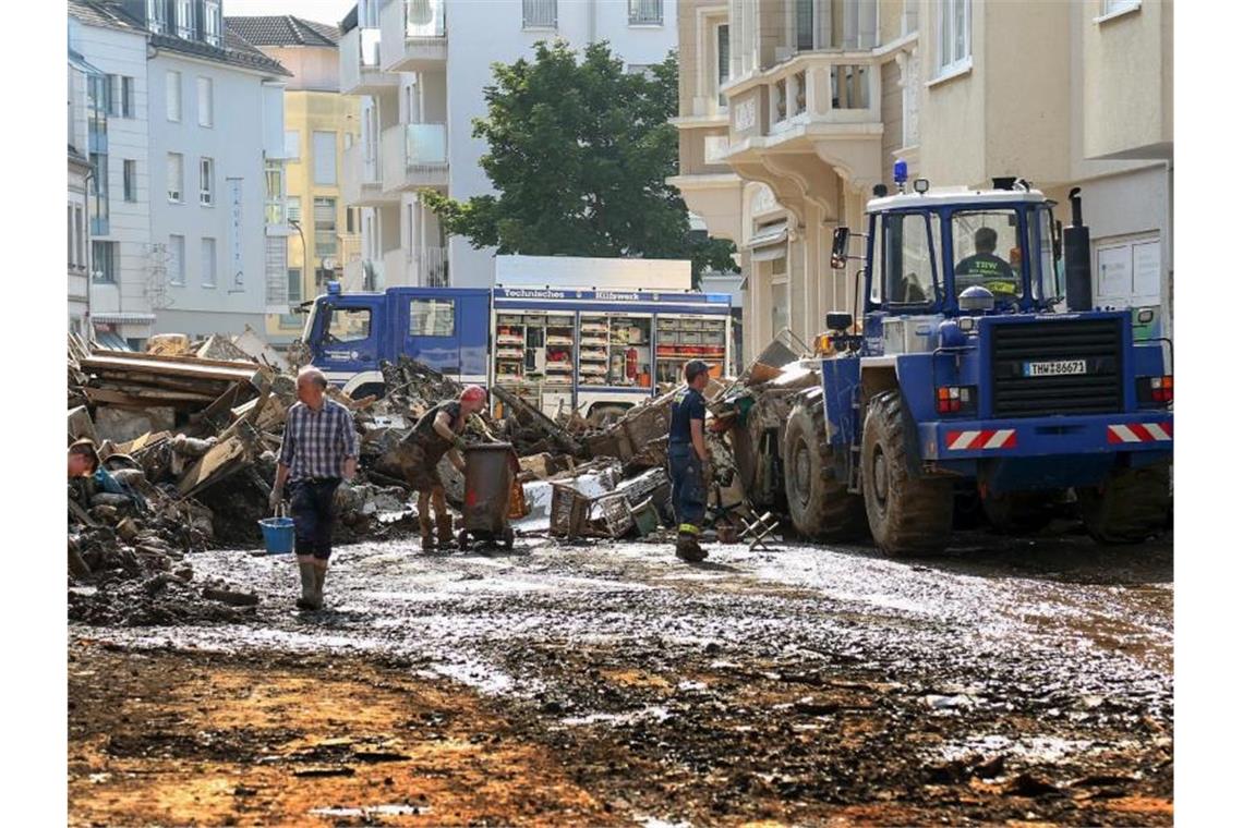 THW-Helfer in Flutgebieten beschimpft und mit Müll beworfen Mitarbeiter des Technischen Hilfswerks (THW) helfen bei Aufräumarbeiten nach der Unwetterkatastrophe in einer verschlammten Straße. Foto: Alexander Mann/THW/dpa