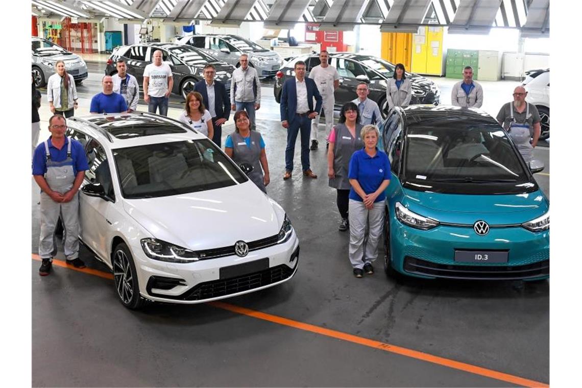 Mitarbeiter des VW-Werks in Zwickau posieren neben einem Golf Variant (l) und einem ID.3. Foto: Hendrik Schmidt/dpa-Zentralbild/dpa