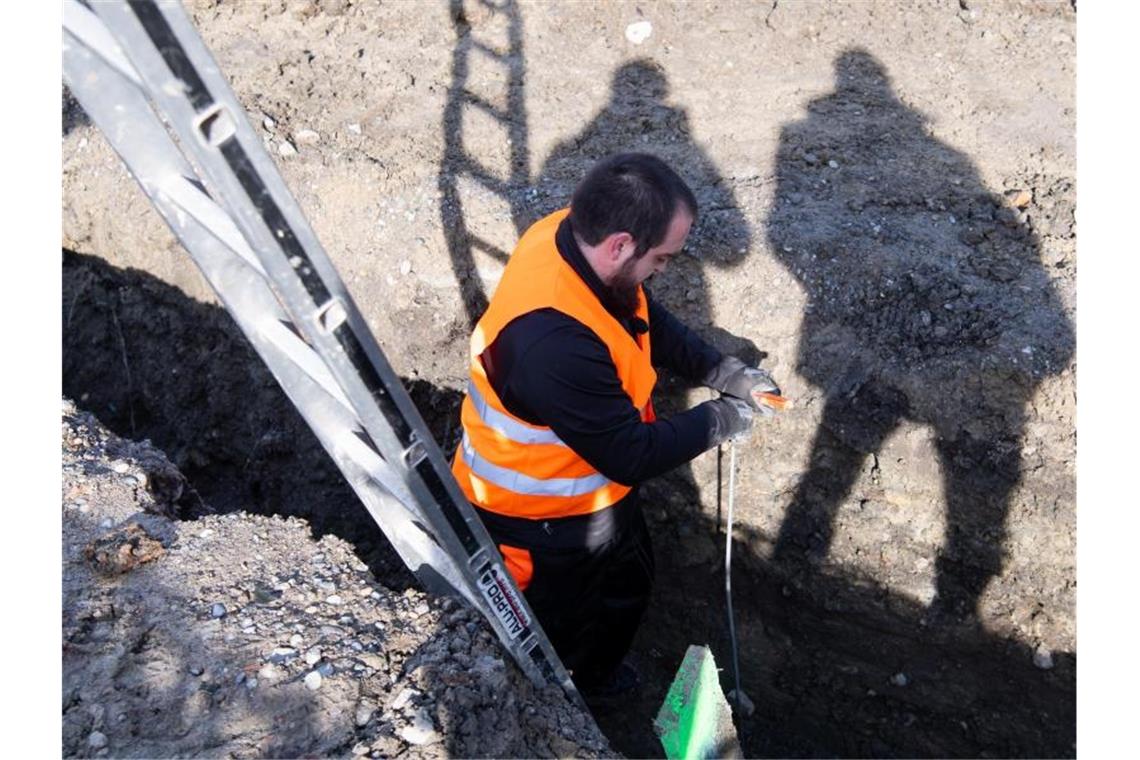 Mitarbeiter im Umbettungsdienst untersucht auf der Baustelle für den neuen Fernbahnhof eine Baugrube. Foto: Sven Hoppe/dpa