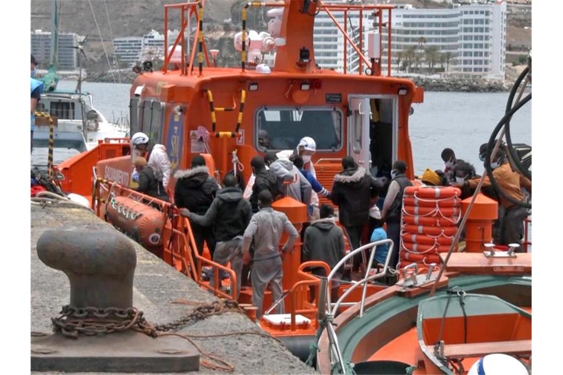 Mitarbeiter in Schutzkleidung der Salvamento Maritimo helfen im Hafen von Arguineguin Migranten an Land. (Archivbild). Foto: Europa Press/dpa