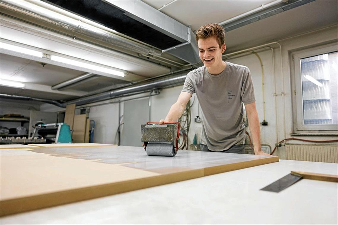 Mitarbeiter Lenny Grotz belegt Platten mit Furnier.