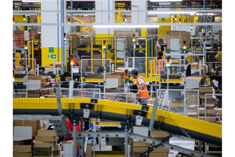 Mitarbeiter mit Mund-Nasen-Schutz packen Pakete in einem Logistikzentrum. Foto: Rolf Vennenbernd/dpa/Archivbild
