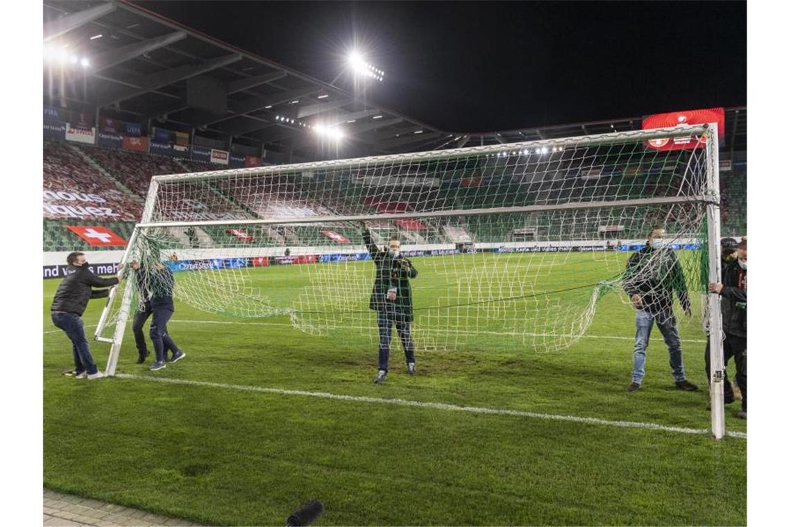Mitarbeiter montieren vor Spielbeginn ein Ersatztor auf dem Spielfeld. Foto: Gian Ehrenzeller/KEYSTONE/dpa
