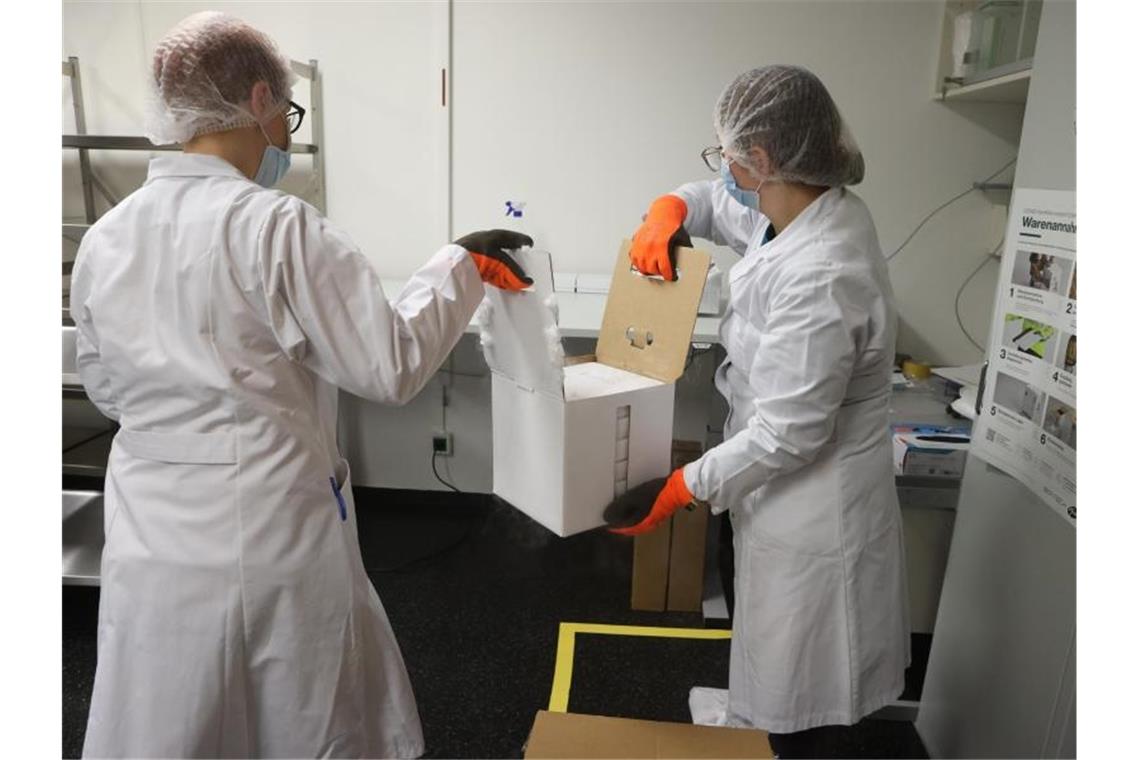 Mitarbeiter öffnen einen Karton mit einigen der ersten knapp 10.000 Dosen des Corona-Impfstoffs für Thüringen. Foto: Bodo Schackow/dpa-Zentralbild/dpa