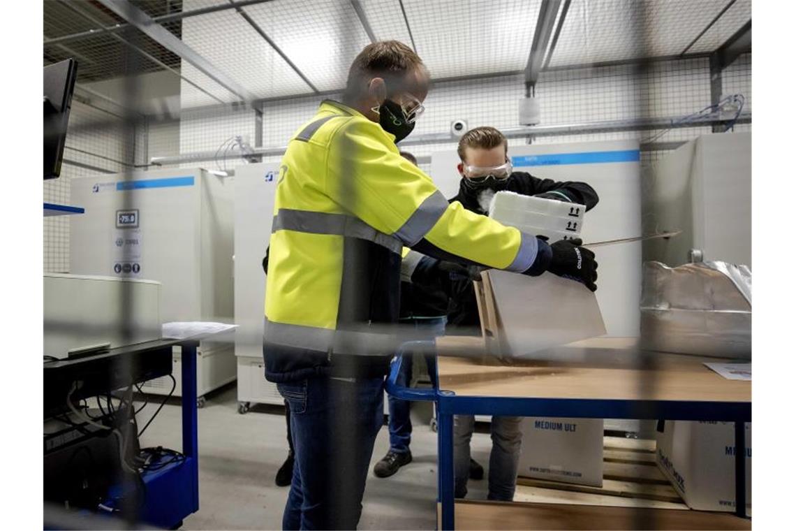 Mitarbeiter packen den ersten Corona-Impfstoffe von Pfizer und Biontech für die Niederlande aus. Foto: Robin Van Lonkhuijsen/ANP/dpa