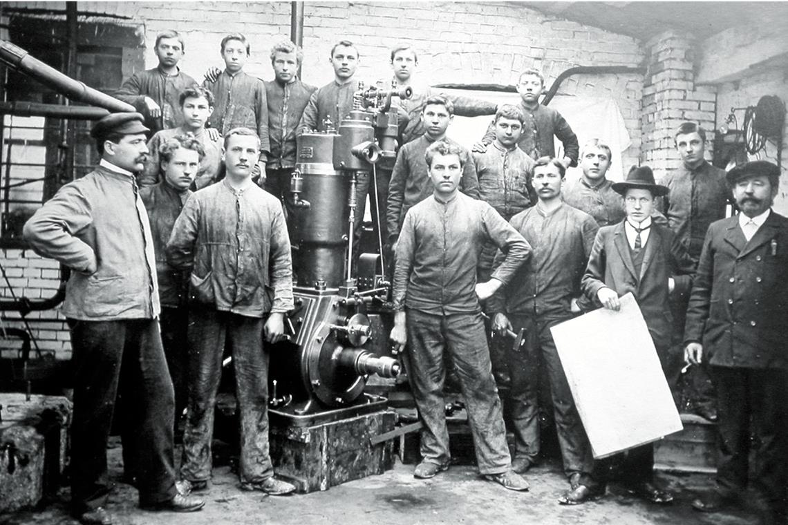 Mitarbeiter präsentieren die erste eigene Motorentwicklung 1903 mit Gottfried Kaelble (rechts) und Carl Kaelble (links).