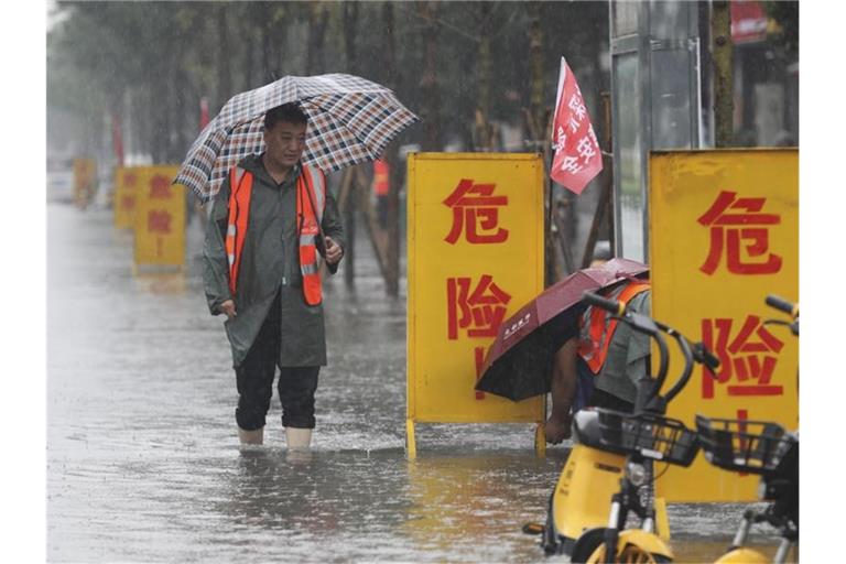 Mitarbeiter stellen Warnschilder auf mit der Aufschrift „Gefahr!“ in einem überschwemmten Gebiet im Kreis Wuzhi in der zentralchinesischen Provinz Henan. Foto: Feng Xiaomin/Xinhua/AP/dpa