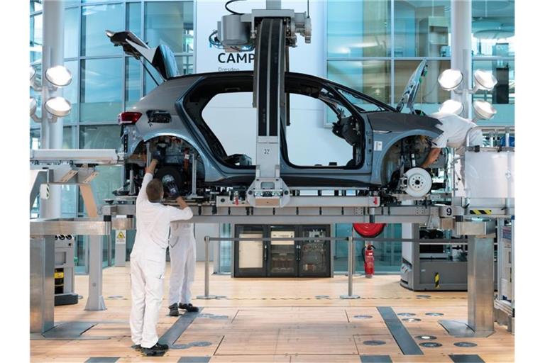 Mitarbeiter von Volkswagen montieren in der Gläsernen Manufaktur von Volkswagen bei der sogenannten „Hochzeit“ die Karosserie und den Antriebsstrang eines VW ID.3. Foto: Sebastian Kahnert/dpa-Zentralbild/dpa