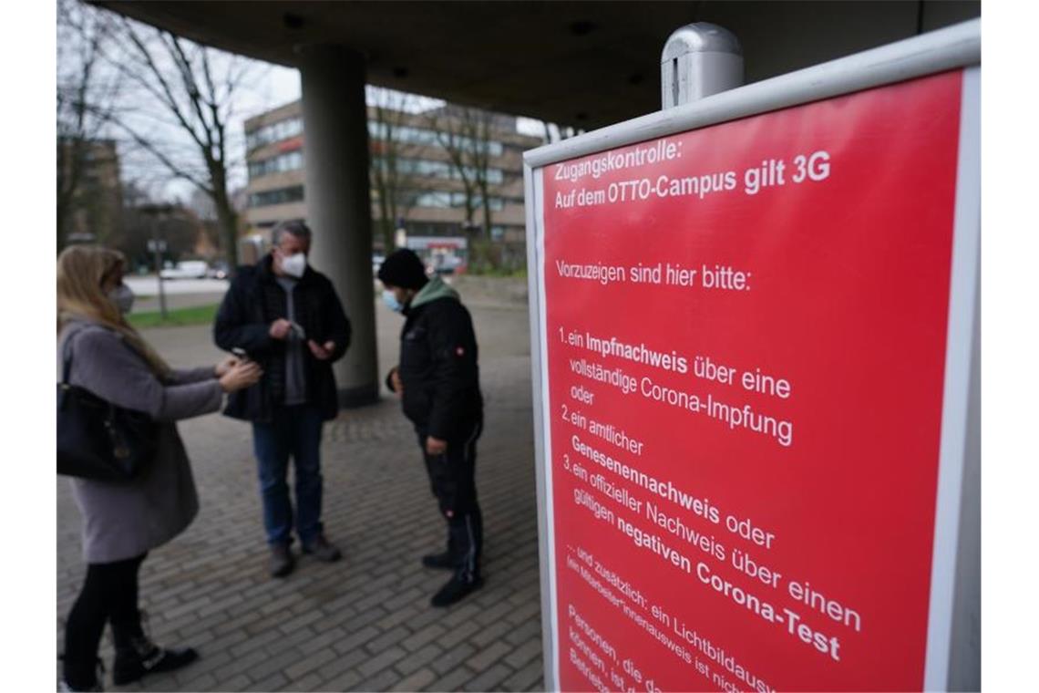 Mitarbeiter werden am Eingang des Otto-Campus der Otto Group gemäß den 3G-Regeln von Sicherheitsmitarbeitern kontrolliert. Foto: Marcus Brandt/dpa