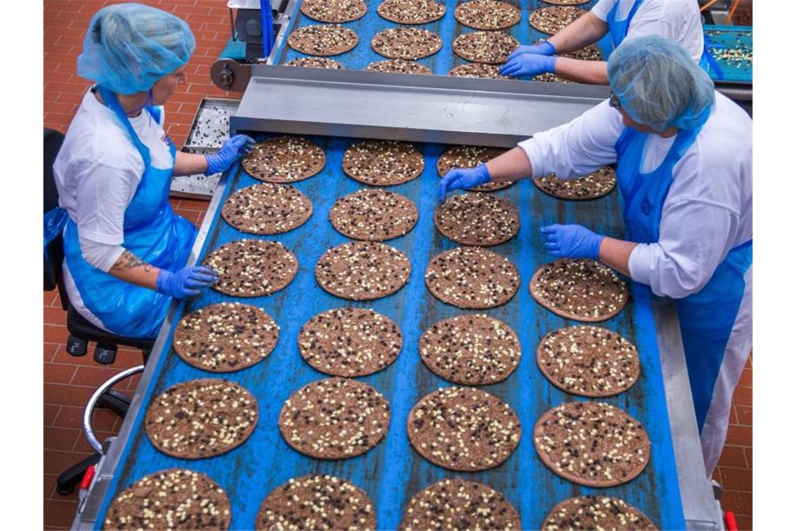 Mitarbeiterinnen belegen im Pizzawerk der Firma Dr. Oetker kakaohaltige Pizzaböden mit Schokoladensplittern. Die Schokoladenpizza wird nach zwei Jahren eingestellt. Foto: Jens Büttner/dpa-Zentralbild/dpa