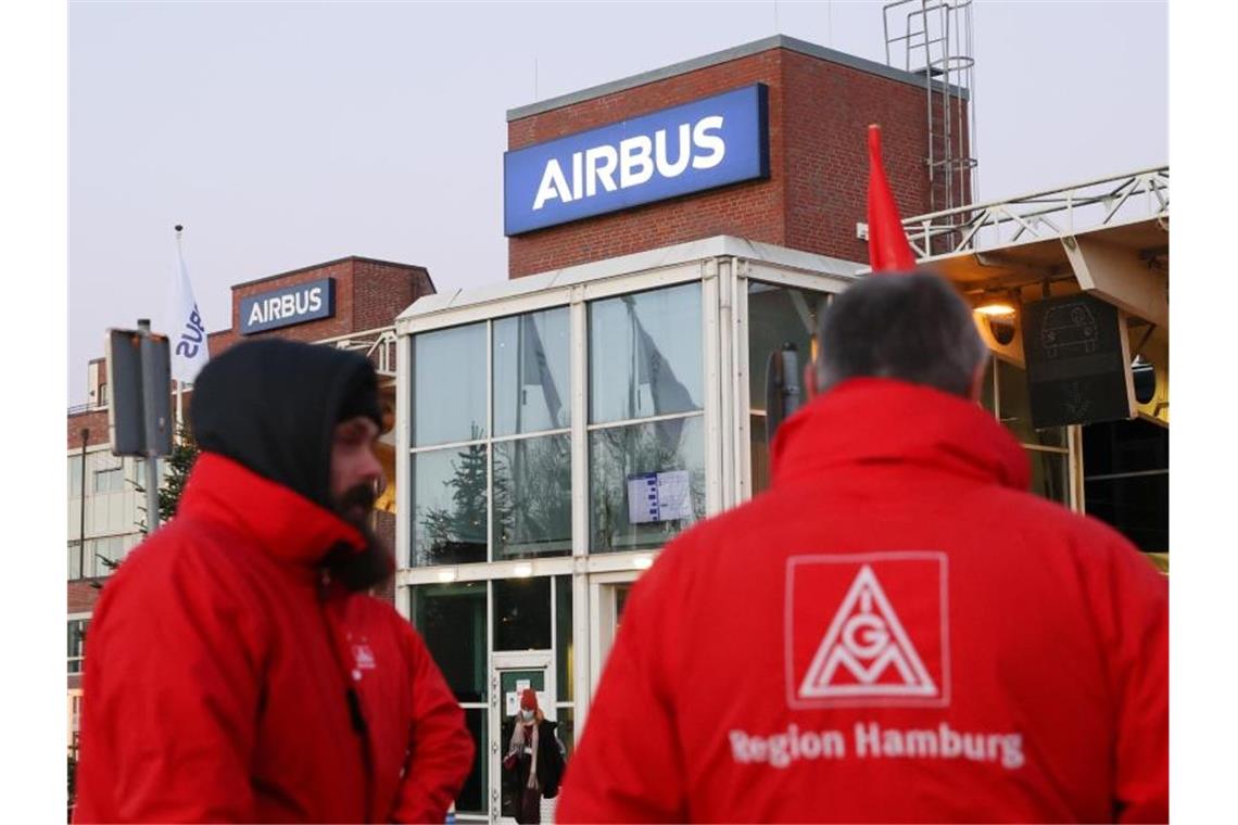 Airbus verhandelt wieder mit IG Metall über Konzernumbau Mitglieder der IG Metall stehen vor einem Werkstor von Airbus in Hamburg-Finkenwerder. Foto: Bodo Marks/dpa