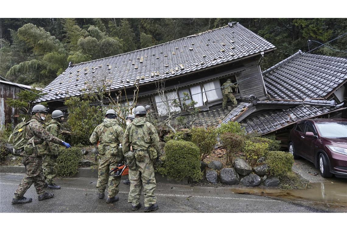 Mitglieder der japanischen Selbstverteidigungskräfte inspizieren ein durch ein Erdbeben eingestürztes Haus in Suzu, Präfektur Ishikawa.