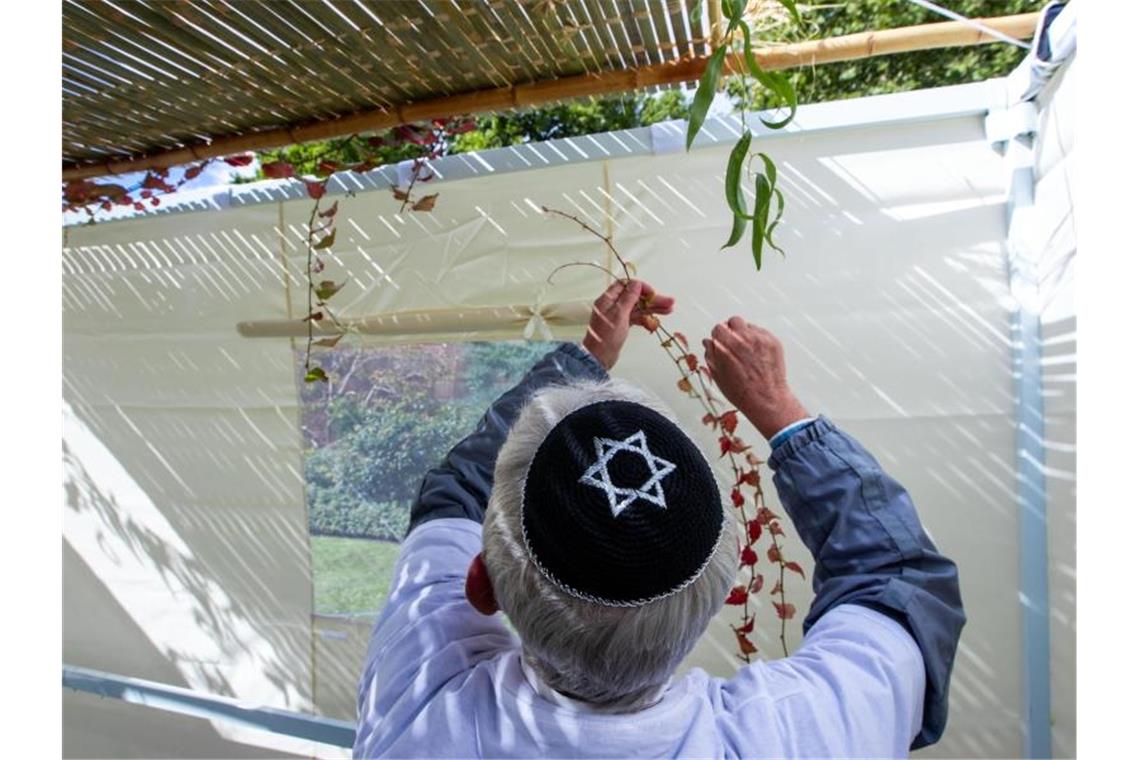 Mitglieder der jüdischen Gemeinde in Schwerin schmücken die traditionelle Laubhütte mit Zweigen und Früchten. Foto: Jens Büttner/dpa-Zentralbild/ZB