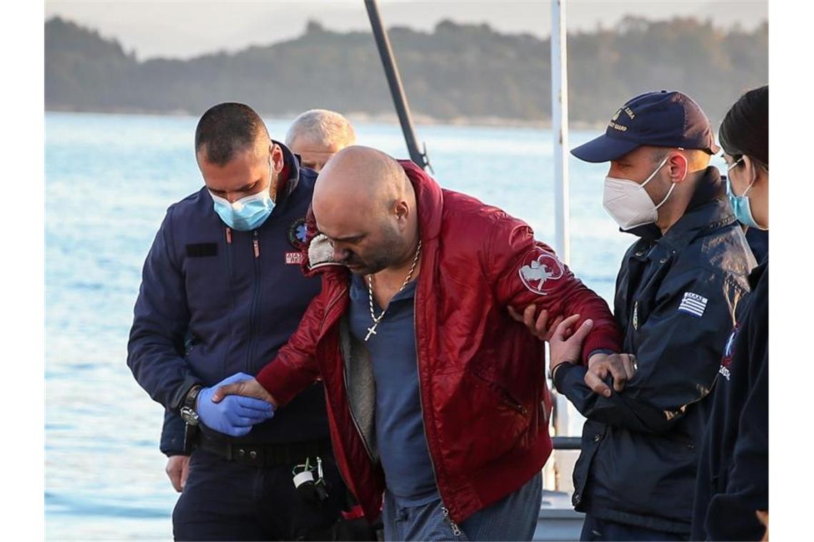 Mitglieder der Küstenwache stützen einen Mann im Hafen, nachdem sie ihn von der brennenden Autofähre gerettet haben. Foto: Eurokinissi/Eurokinissi via ZUMA Press Wire/dpa