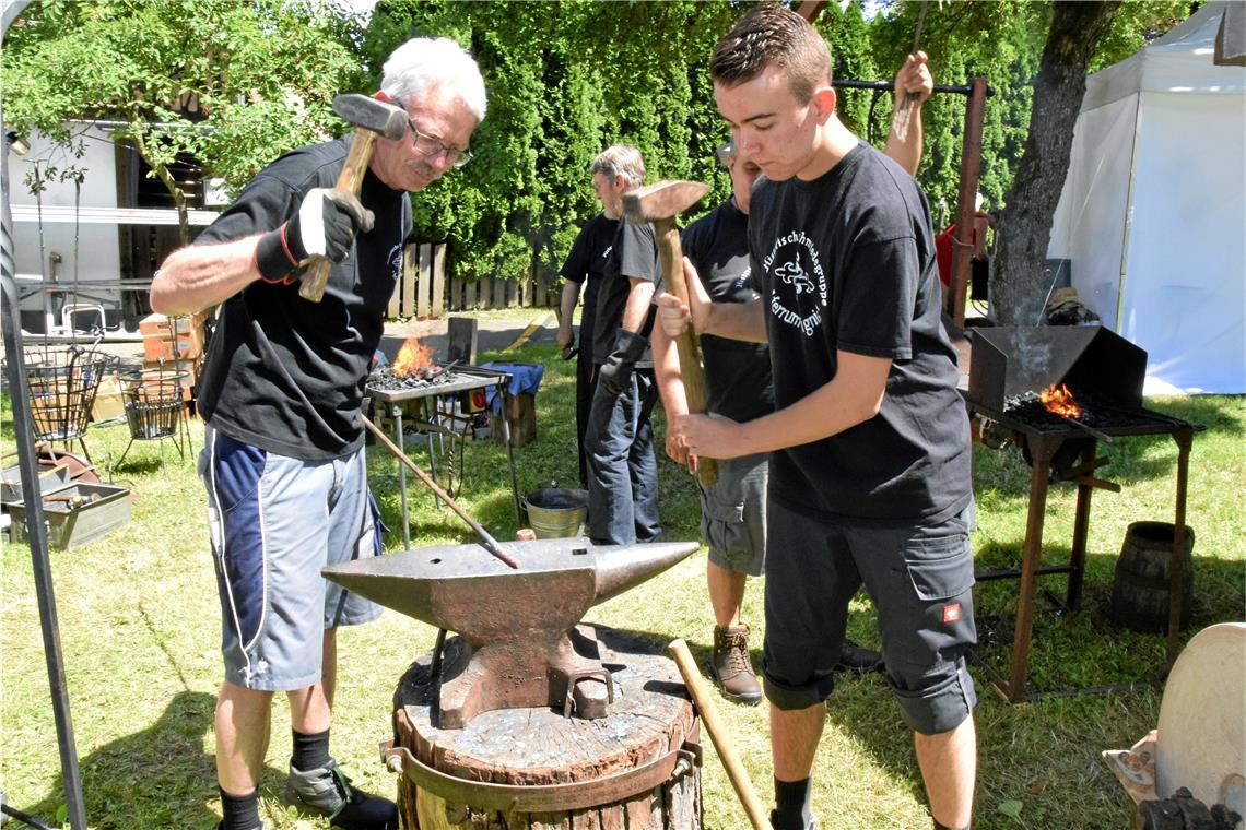 Mitglieder der Schmiedegruppe „Eisen und Feuer“ bearbeiten Eisen auf dem Amboss.