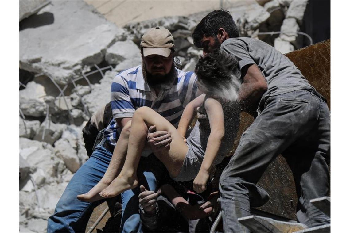 Mitglieder der syrischen Weißhelme und Freiwillige retten ein verletztes Kind aus den Trümmern eines Gebäudes, das bei einem Luftangriff durch die syrischen Regierungskräfte beschädigt wurde. Foto: Anas Alkharboutli