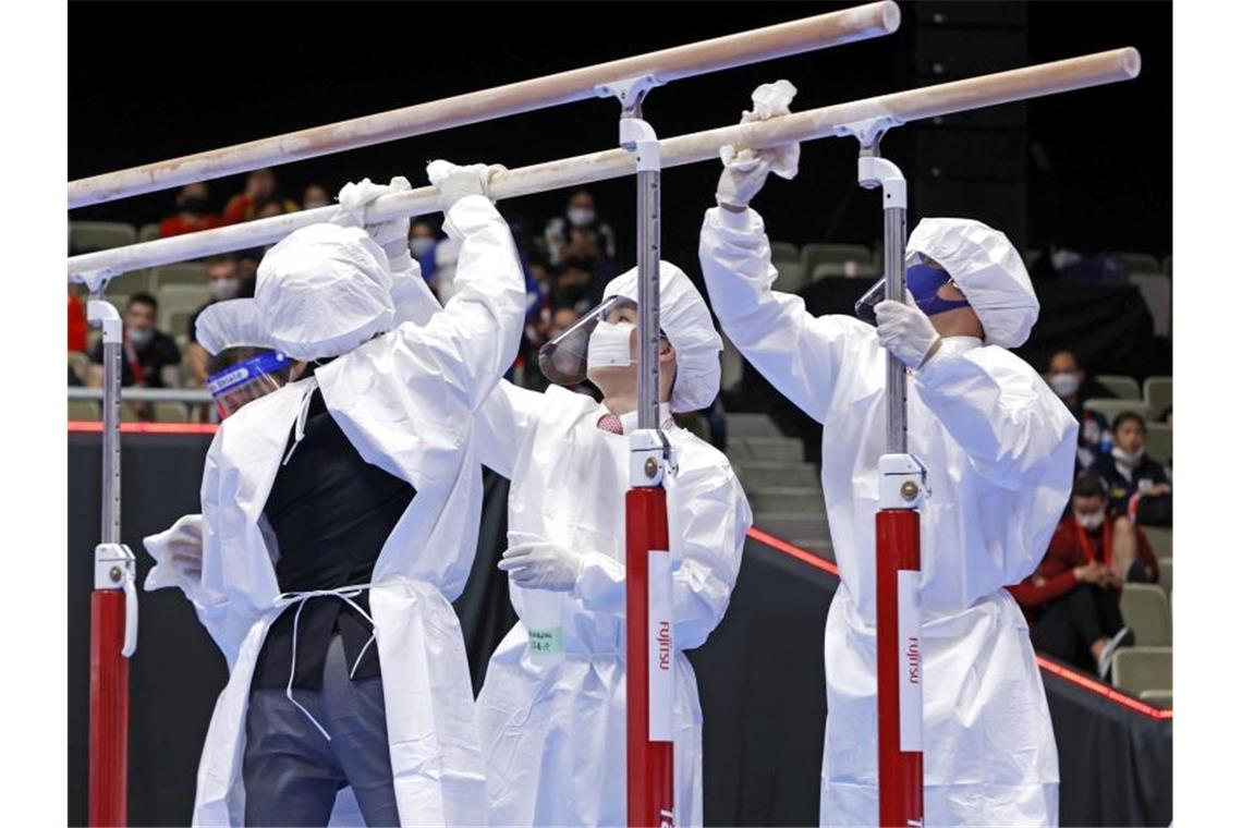 Unangenehmer Gegenspieler: Corona bestimmt weiter den Sport Mitglieder des Organisationsteams desinfizieren in Schutzanzügen und mit Mund-Nasen-Schutz die Geräte. Foto: -/kyodo/dpa/Archivbild