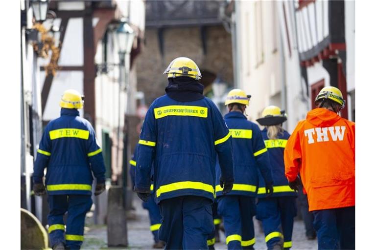 Mitglieder des Technischen Hilfswerks (THW) gehen bei Räumarbeiten nach der Unwetter-Katastrophe in Nordrhein-Westfalen durch einen zerstörten Ort. Foto: Thomas Banneyer/dpa