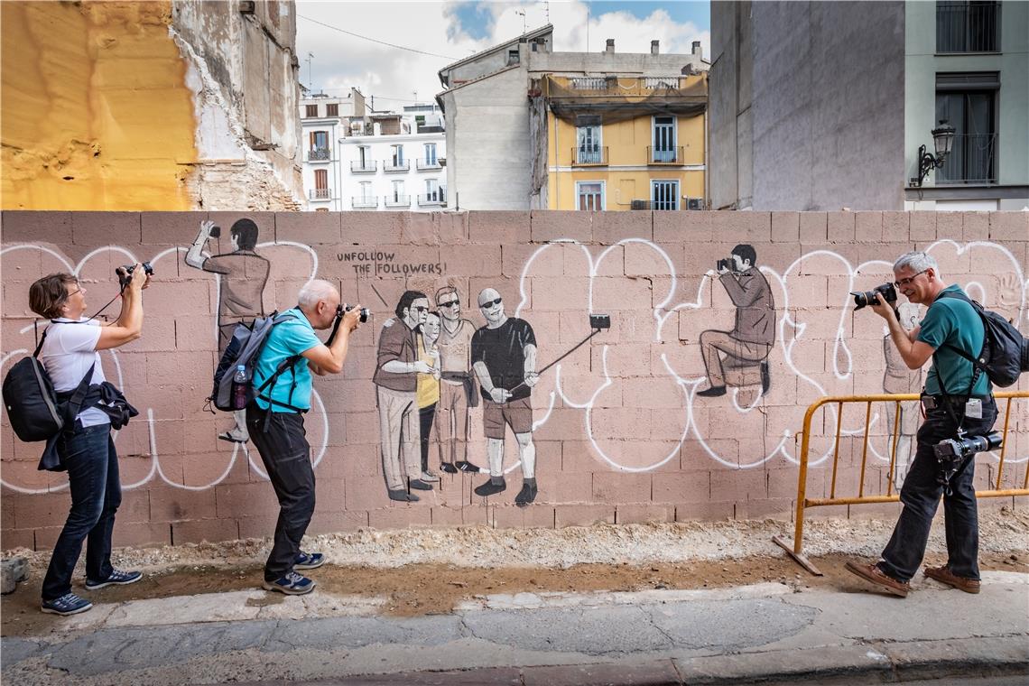 Mitglieder einer Fotogruppe fotografieren eine bemalte Mauer in Valencia.