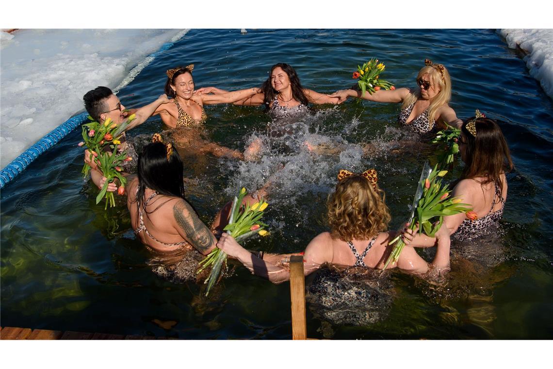 Mitglieder eines Winterschwimmclubs feiern in einem Eisloch den Internationalen Frauentag.