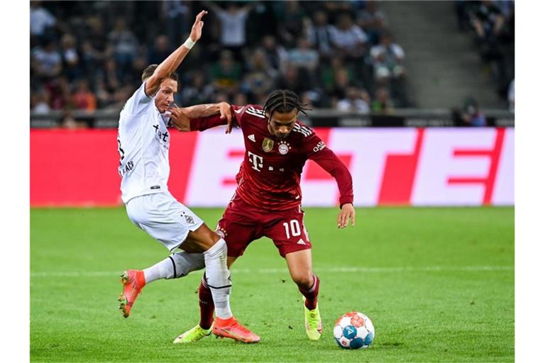 Mönchengladbachs Hannes Wolf (l) und Bayerns Leroy Sané kämpfen um den Ball - am Ende der Partie steht es 1:1. Foto: Federico Gambarini/dpa