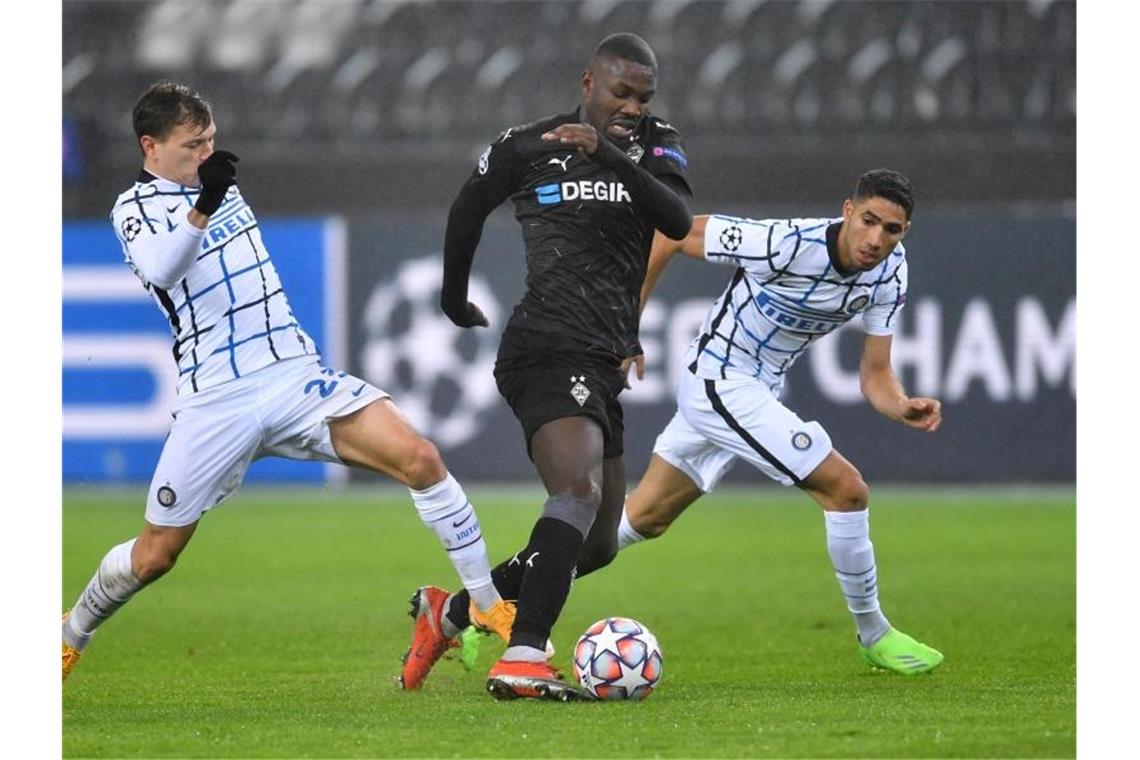 Wieder Inter! - Gladbach bangt um Weiterkommen in der Gruppe Mönchengladbachs Marcus Thuram (M) führt den Ball eng am Fuß - die Mailänder Nicolo Barella (l) und Achraf Hakimi versuchen diesen zu erobern. Foto: Marius Becker/dpa