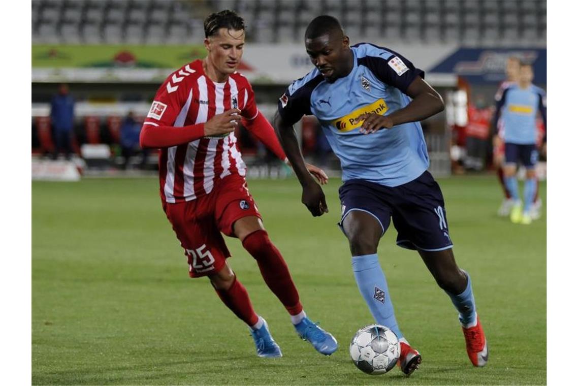 Reaktionen: SC Freiburg - Borussia Mönchengladbach (1:0) Mönchengladbachs Marcus Thuram (r) und Freiburgs Robin Koch kämpfen um den Ball. Foto: Ronald Wittek/epa/Pool/dpa