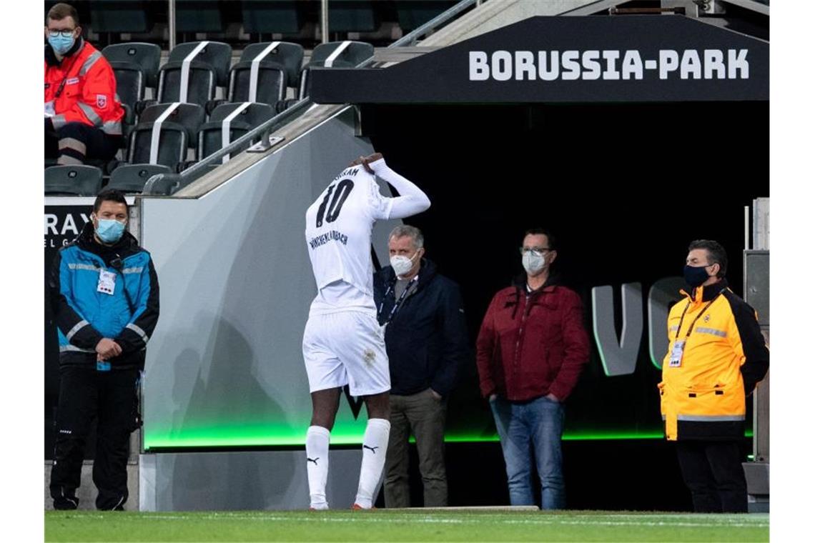 Mönchengladbachs Marcus Thuram verlässt nach seiner Spuckattacke das Feld. Foto: Marius Becker/dpa-Pool/dpa