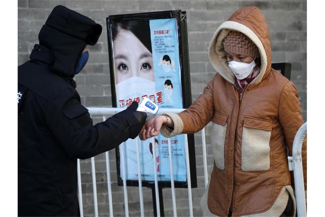 7 von 14 Quarantäne-Patienten in Bayern sind wieder daheim Momentaner Alltag in Peking: Ein Sicherheitsmann misst die Temperatur bei einer Frau. Foto: Andy Wong/AP/dpa