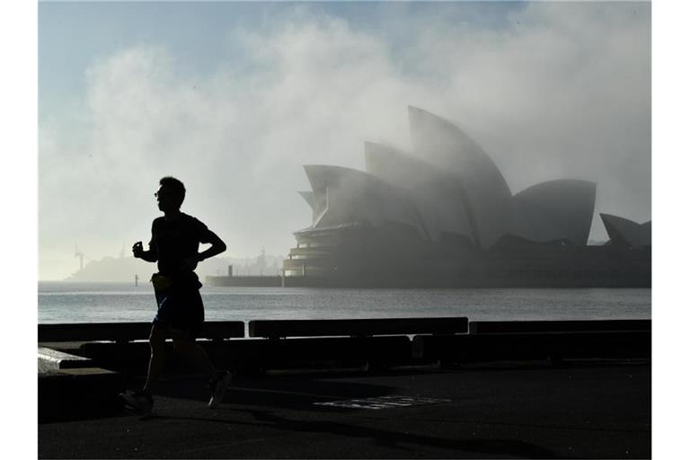 Morgennebel über dem Opernhaus in Sydney. Unentschlossene Bewohner Australiens sollen jetzt mit Hilfe einer Millionen-Lotterie dazu bewegt werden, sich gegen das Coronavirus impfen zu lassen. Foto: Joel Carrett/AAP/dpa