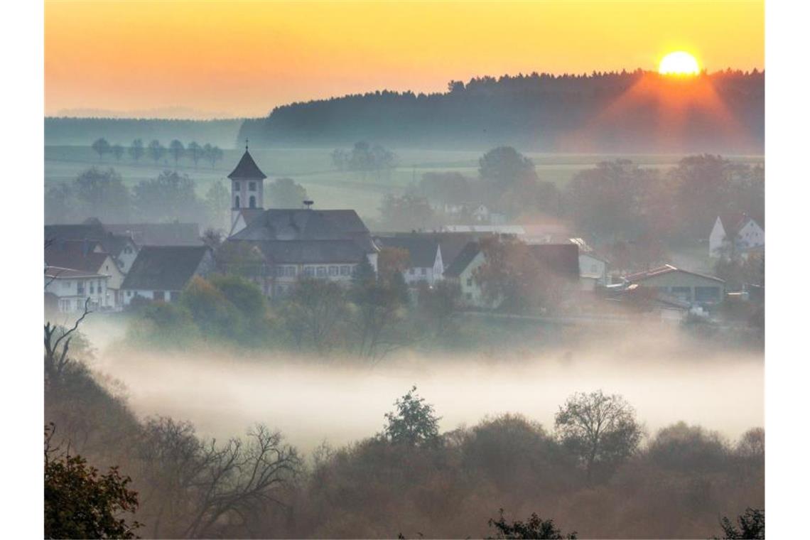 Start in eine kühle Woche in Baden-Württemberg Morgennebel über einer Ortschaft. Foto: Thomas Warnack/dpa