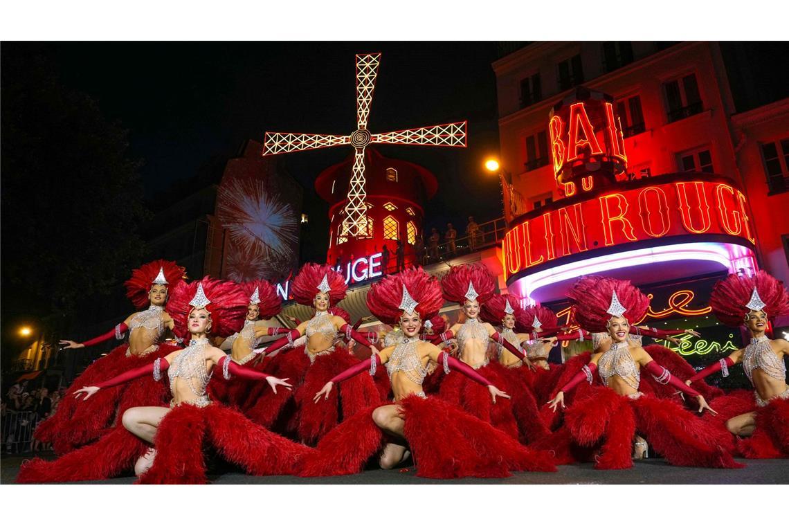 Bilder des Tages Moulin Rouge-Tänzerinnen und -Tänzer agieren vor den neuen Flügel der Windmühle des Moulin Rouge, die sich drehen, während das Kabarett in Paris seine Wiederinbetriebnahme feiert. Vierzehn Monate nach ihrem Sturz wurden die Flügel des Moulin Rouge wieder installiert und drehen sich nun wieder, womit eine mehr als 135 Jahre alte Tradition wiederbelebt wird.