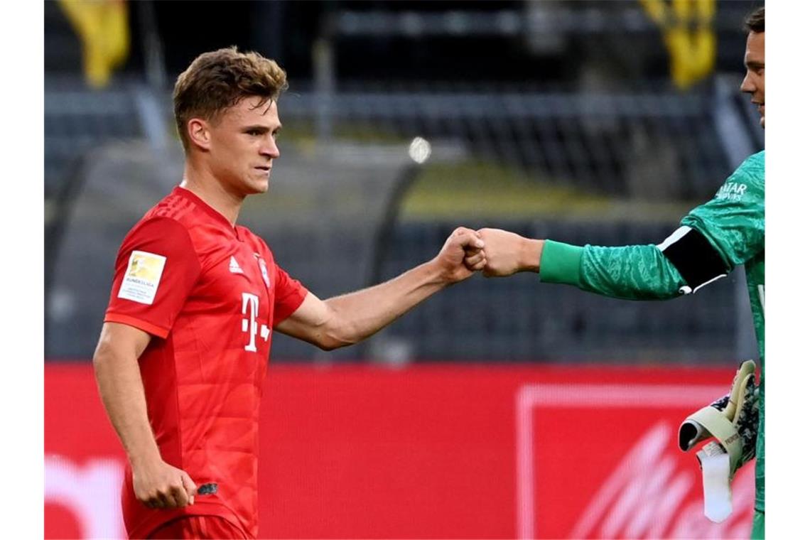 Münchens Matchwinner Joshua Kimmich (l) begrüßt Torwart Manuel Neuer. Foto: Federico Gambarini/dpa-Pool/dpa