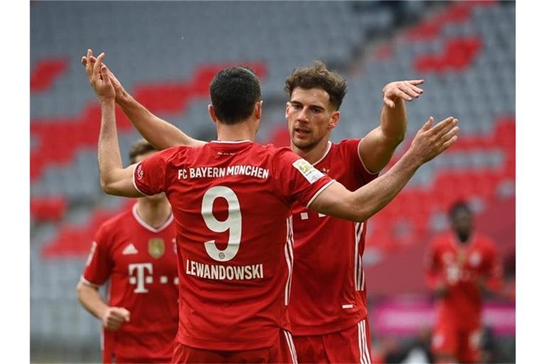 Münchens Robert Lewandowski (M) bejubelt sein Tor zum 2:0 mit Leon Goretzka. Foto: Sven Hoppe/dpa