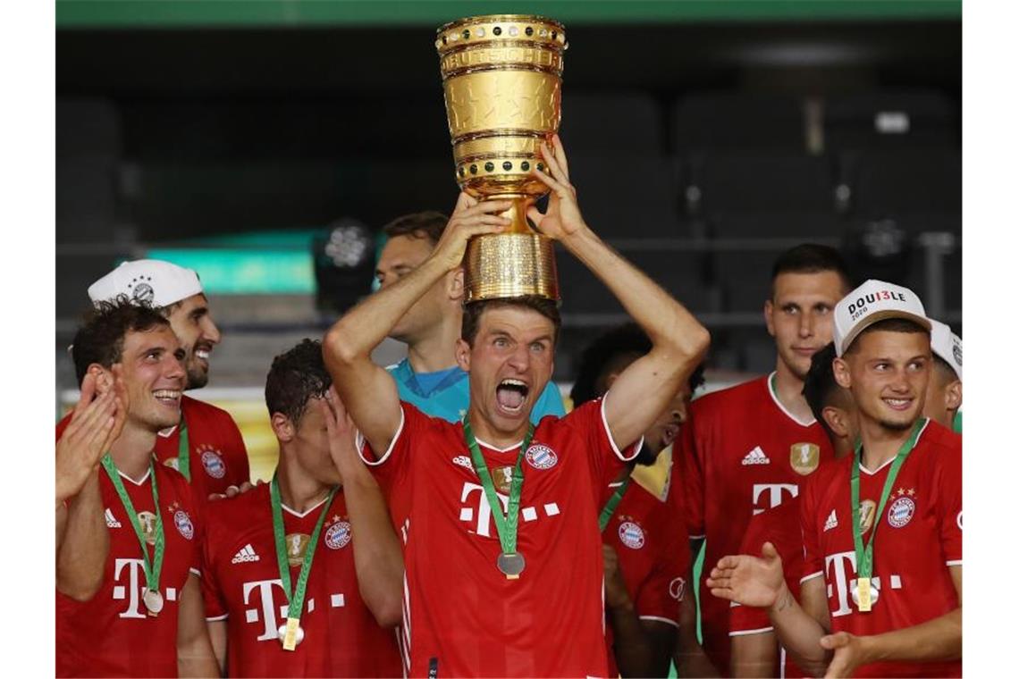 Münchens Thomas Müller hält die Trophäe nach dem Spiel hoch. Foto: Alexander Hassenstein/Getty Images Europe/Pool/dpa