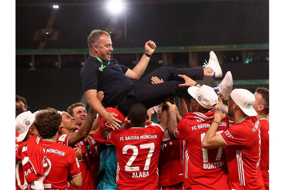 Münchens Trainer Hansi Flick wird von seinen Spielern in die Luft geworfen. Foto: Alexander Hassenstein/Getty Images Europe/Pool/dpa