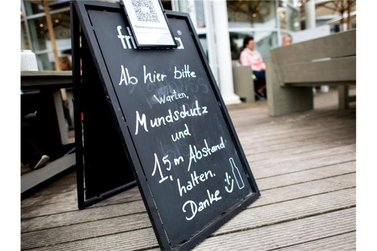„Mundschutz und 1,5 m Abstand halten“ steht auf einem Schild vor einem Lokal auf der Nordseeinsel Norderney. Niedersachsen öffnet den Tourismus zunächst nur für die Einwohner des eigenen Bundeslandes. Foto: Hauke-Christian Dittrich/dpa