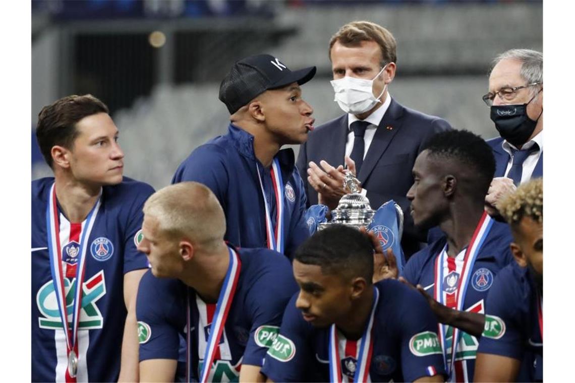 Musste die Glückwünsche von Präsident Emmanuel Macron (M) zum PSG-Pokalsieg auf Krücken entgegennehmen: Kylian Mbappé (3.v.l.). Foto: Francois Mori/AP/dpa