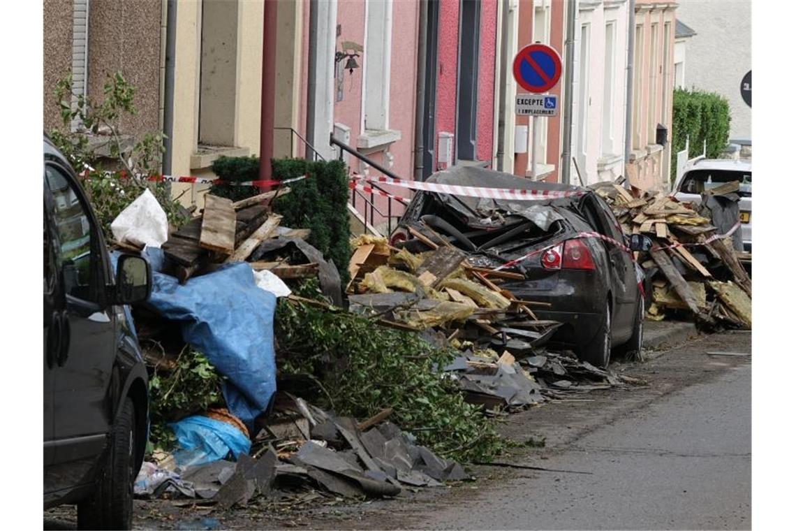 Nach dem schweren Unwetter liegen Trümmer auf einer Straße im luxemburgischen Petingen. Foto: Harald Tittel