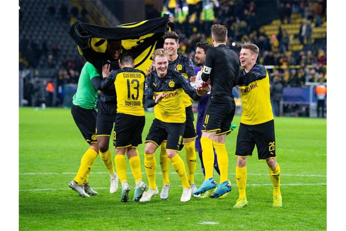 Schützenhilfe von Barca: BVB zittert sich ins Achtelfinale Nach dem Spiel gegen Slavia Prag tanzen Dortmunds Spieler erleichtert vor den Fans auf dem Spielfeld. Foto: Guido Kirchner/dpa