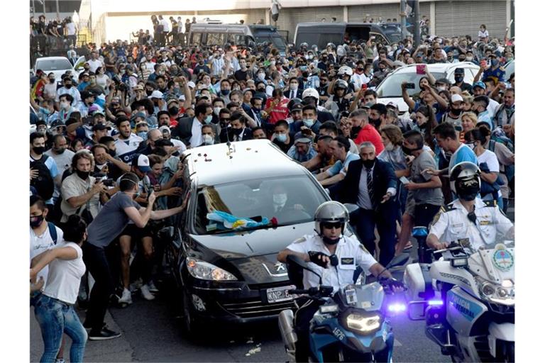 Nach dem Tod von Diego Maradona verlässt der Leichenwagen mit den sterblichen Überresten das Regierungsgebäude - begleitet von zahlreichen Fans. Foto: Ferrari Raul/telam/dpa