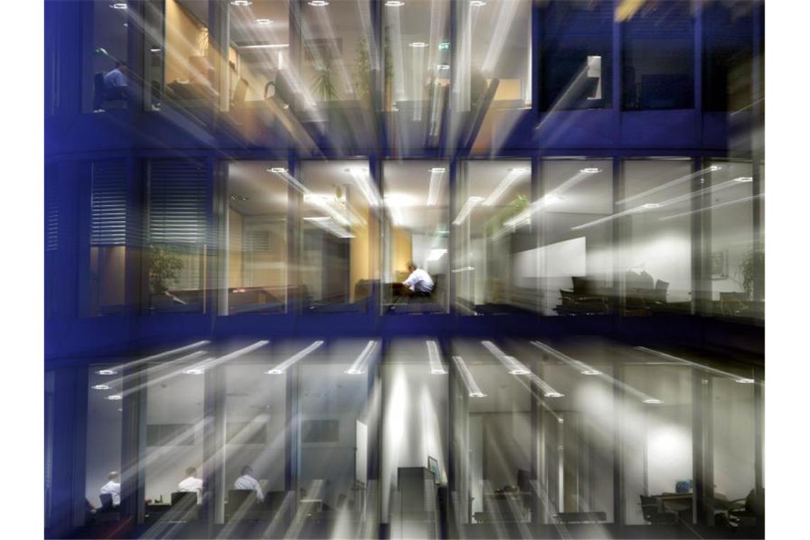 Nach Einbruch der Dunkelheit sitzt ein Angestellter in seinem Büro am Schreibtisch. (Archivbild). Foto: picture alliance / dpa